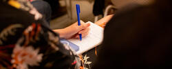 closeup of a person’s hand writing on a notepad