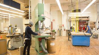 students work at several fabrication stations in a spacious workshop