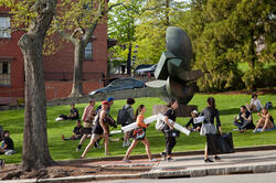 Students carry art supplies and walking past RISD Beach on a beautiful day