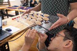 a student attaches wires to a glass device with several nodes, as another student holds the glass attachment surface