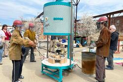 Students in protective gear prepare to remove fired ceramics pieces from the new raku kiln