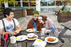 three students sit at an outdoor dining table